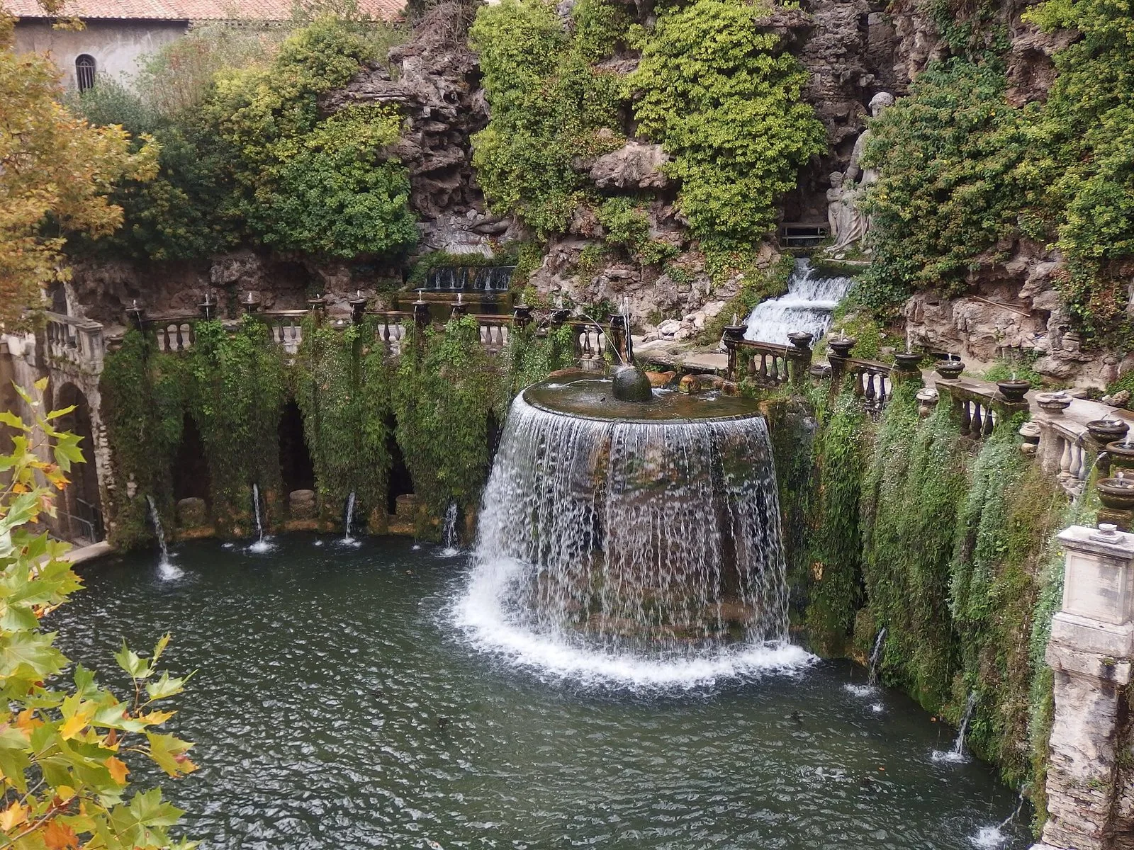 La Fontana dell'Ovato a Villa d'Este: una cascata d'acqua a ventaglio cade in una vasca ovale, circondata da un emiciclo di nicchie e balaustre coperte di vegetazione rampicante